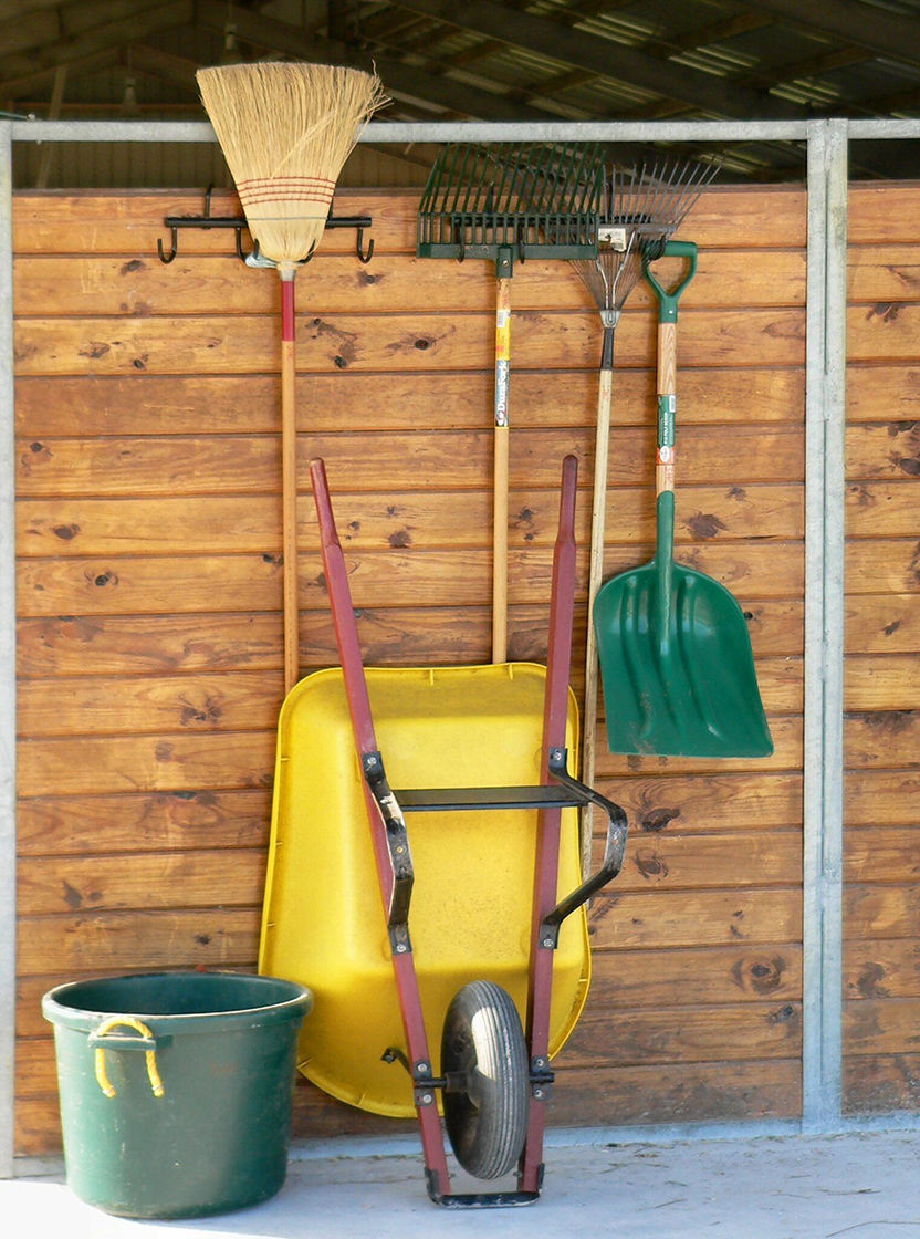 Barn cleaning tools lined up against a wall