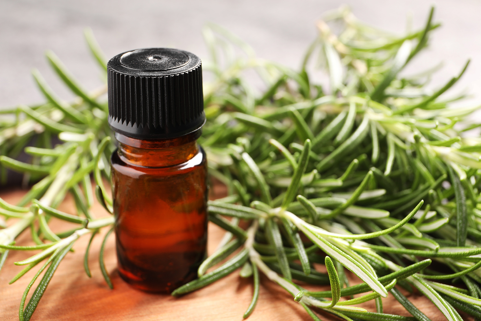 An essential oil bottle surrounded by rosemary sprigs